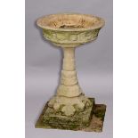 CAST STONE BIRD BATH, of sandstone colour, the circular dish with a glazed interior and fish & shell