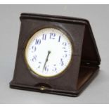 LEATHER CASED TRAVEL CLOCK, the 3 3/4" enamelled dial with blue arabic numerals on a manual wind