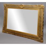 GILT GESSO WALL MIRROR, late 19th century, the rectangular plate inside a pierced frame centred on