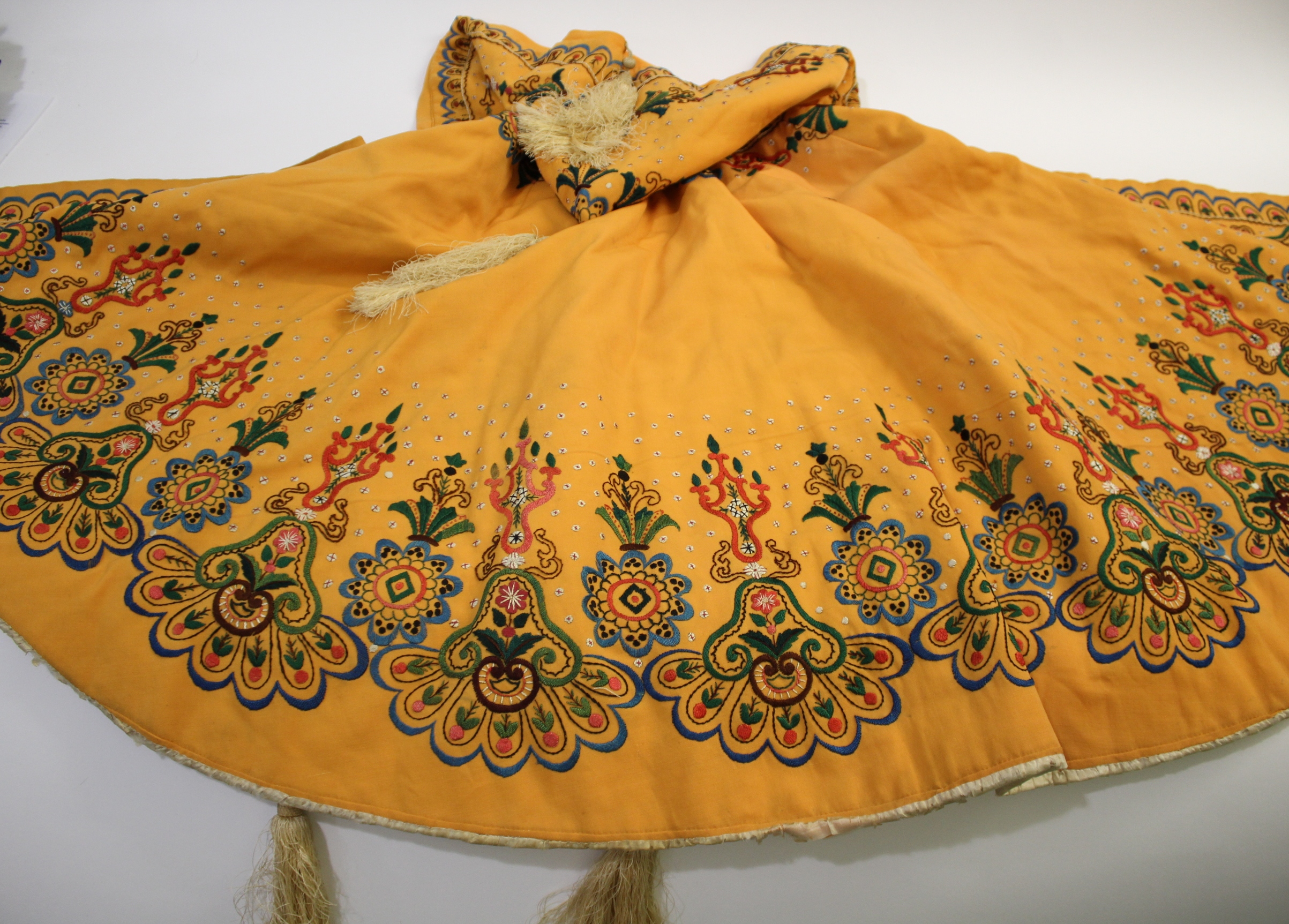 EARLY 20THC CAPE probably Eastern European, the orange wool cape lined with ivory coloured silk, and