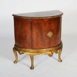 An early 20th century George III style yew wood and parcel gilt demi lune side cabinet, the shaped