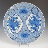 A Japanese blue and white porcelain charger, late 19th/ early 20th century, decorated with panels of