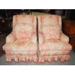 A pair of floral upholstered country house armchairs, with loose cushions, raised on tapered