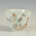 A Chinese porcelain tea bowl, Qing Dynasty, decorated with a female kneeling before a table, iron