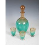 A Monart decanter, stopper and three glasses, shape QE, mottled green with gold inclusions,
