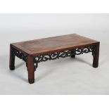 A Chinese dark wood Kang table, Qing Dynasty, the rectangular panelled top above a pierced and