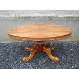 A 19th century rosewood snap top supper table, the hinged oval top raised on a foliate carved column