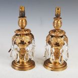 A pair of 19th century gilt metal candlesticks, with foliate cast canopy suspending facet cut