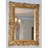 A late 19th/ early 20th century giltwood wall mirror, the pierced, scroll and shell carved frame