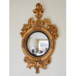 A 19th century giltwood wall mirror, the foliate and scroll carved frame enclosing a circular convex