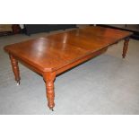 A Victorian oak extending dining table, the rectangular top with canted angles, enclosing two