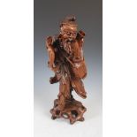 A Chinese carved wood figure of a fisherman, late 19th/ early 20th century, with shell inlaid eyes