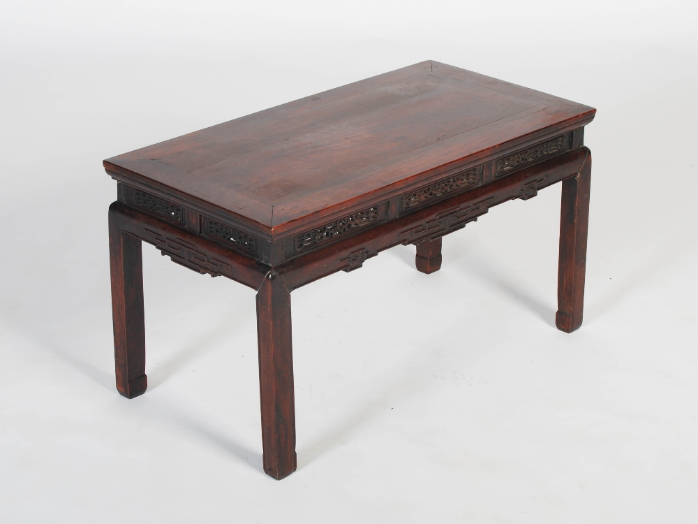 A Chinese dark wood low table, Qing Dynasty, the rectangular panelled top above a pierced and scroll
