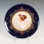 A Vienna porcelain cobalt blue ground cabinet plate titled 'LIEBESERWACHEN', decorated with a bust