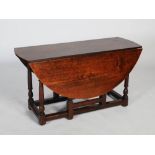 A 19th century oak drop leaf dining table, the oval top with twin drop leaves, raised on four