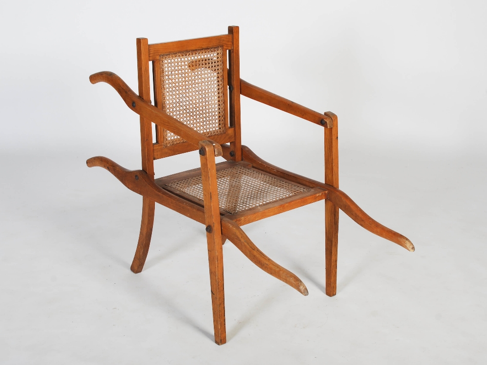 An early 20th century folding bathing chair, with cane work back and seat, the reverse inscribed '