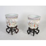 A pair of modern Chinese porcelain jardinieres and stands, 20th century, decorated with figures in a