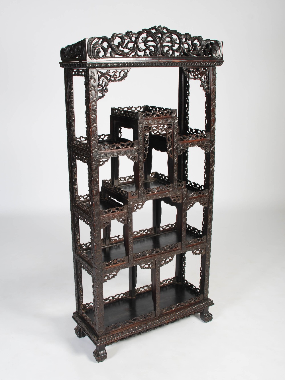 A Chinese dark wood display cabinet, Qing Dynasty, the pierced and scroll carved foliate frieze