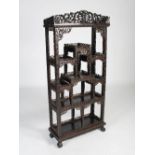 A Chinese dark wood display cabinet, Qing Dynasty, the pierced and scroll carved foliate frieze