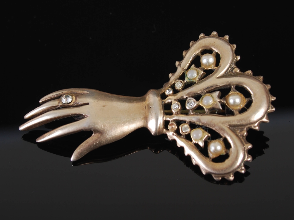 An early 20th century white metal, paste and simulated split pearl brooch in the form of a hand,