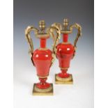 A pair of late 19th century ormolu mounted polished red stone twin handled urns later mounted as