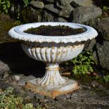 A set of three late 19th/ early 20th century white painted cast iron garden urns, on square plinth