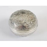 A late 19th century Indian silver circular box and cover, with embossed decoration of figures,