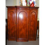 A Victorian mahogany breakfront wardrobe, with three arched panel doors, the central door opening to