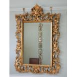 A 20th century giltwood wall mirror, the foliate and scroll carved frame enclosing a rectangular