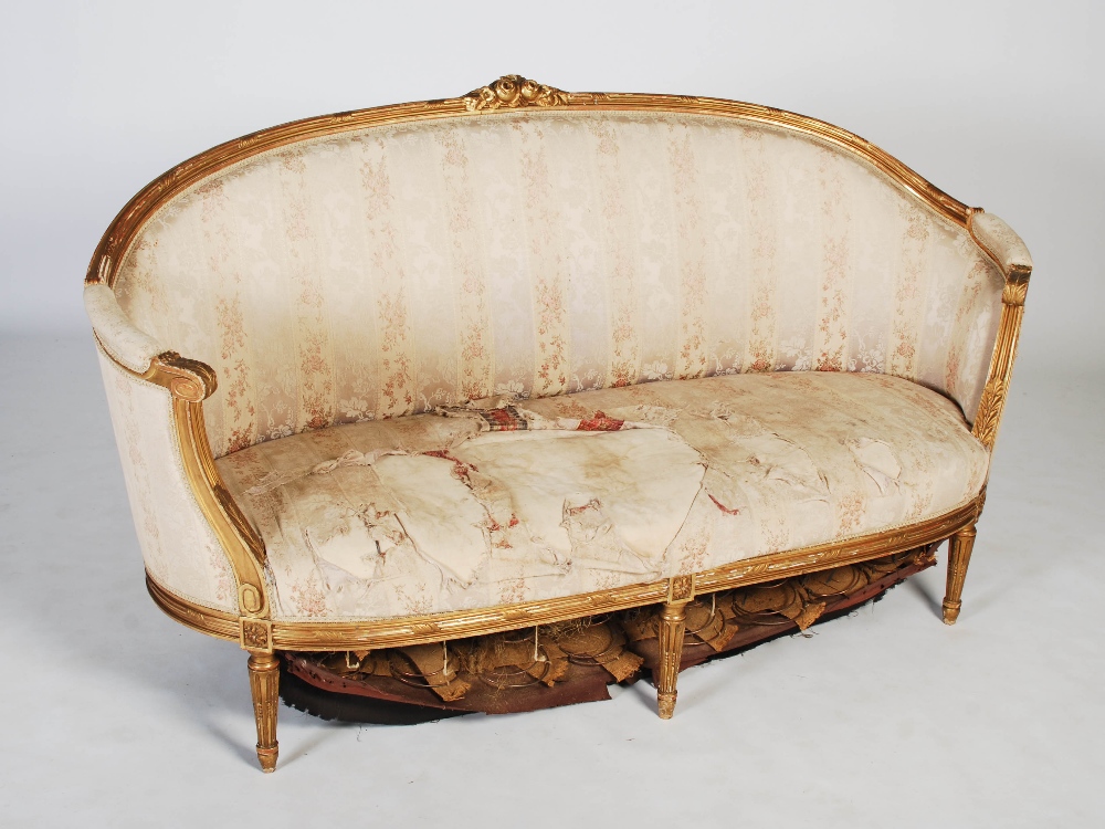 A late 19th century gilt wood sofa, the reeded top rail centred with flower and foliate carved