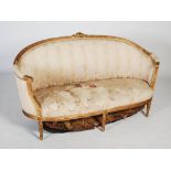 A late 19th century gilt wood sofa, the reeded top rail centred with flower and foliate carved