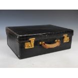 An early 20th century black leather simulated crocodile skin suitcase, with gilt metal lever locks