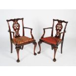 A pair of George III style mahogany elbow chairs, the scroll and foliate carved top rails above