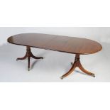 A George III style mahogany twin pedestal dining table, enclosing two additional leaves, raised on