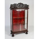 A Chinese dark wood display cabinet, late Qing Dynasty, the cornice centred with a pierced and