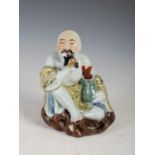 A Chinese porcelain figure of kneeling fisherman, late Qing Dynasty, modelled kneeling smoking a