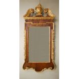 A 19th century George III mahogany and parcel gilt wall mirror, the broken scroll pediment centred