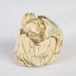 A Chinese ivory figure group, Qing Dynasty, carved as a bearded man curled up sleeping on his knees,