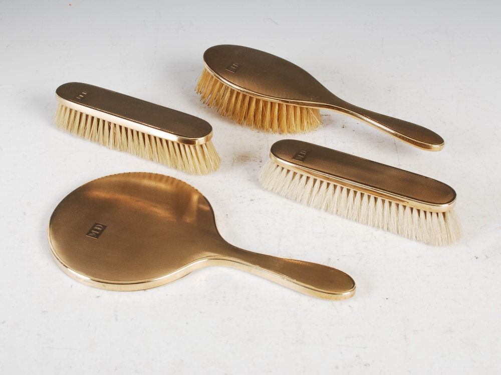 A 9ct gold four piece dressing table set, comprising; handheld mirror, single brush and pair of