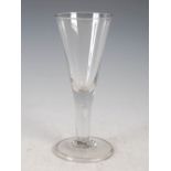 A large 18th/19th century oversized wine glass, the drawn conical bowl on a clear glass stem with