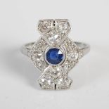 An Art Deco white metal sapphire and diamond ring, centred with a round cut sapphire in a panelled