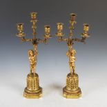 A pair of late 19th century ormolu three light candelabra, each modelled with a cherub supporting