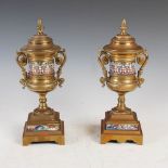 A pair of late 19th century gilt metal and champleve enamel twin handled urns, with acorn shaped