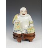 A Chinese porcelain figure of a laughing Buddha, late 19th/ early 20th century, decorated in