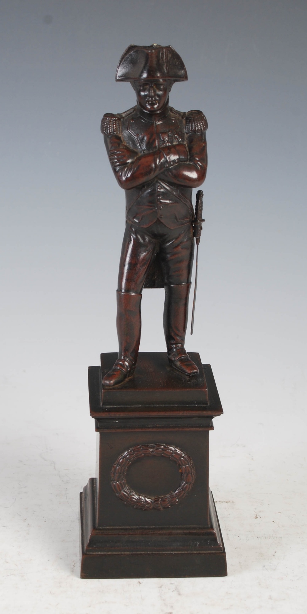 A bronzed spelter figure of Napoleon Bonaparte, modelled standing on square plinth base with oval