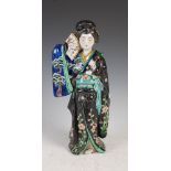A Japanese porcelain figure of a bijin, late 19th/early 20th century, modelled standing holding a