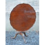 A George III mahogany snap top occasional table, the hinged circular top with a carved edge,