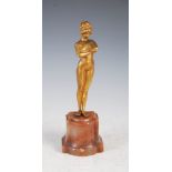 An early 20th century gilt bronze figure of a nude female, modelled standing with arms crossed,
