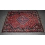 A Persian rug, 20th century, the madder ground centred with a lozenge shaped medallion within a