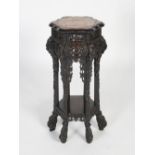 A Chinese dark wood urn stand, Qing Dynasty, the shaped hexagonal top centred with a mottled